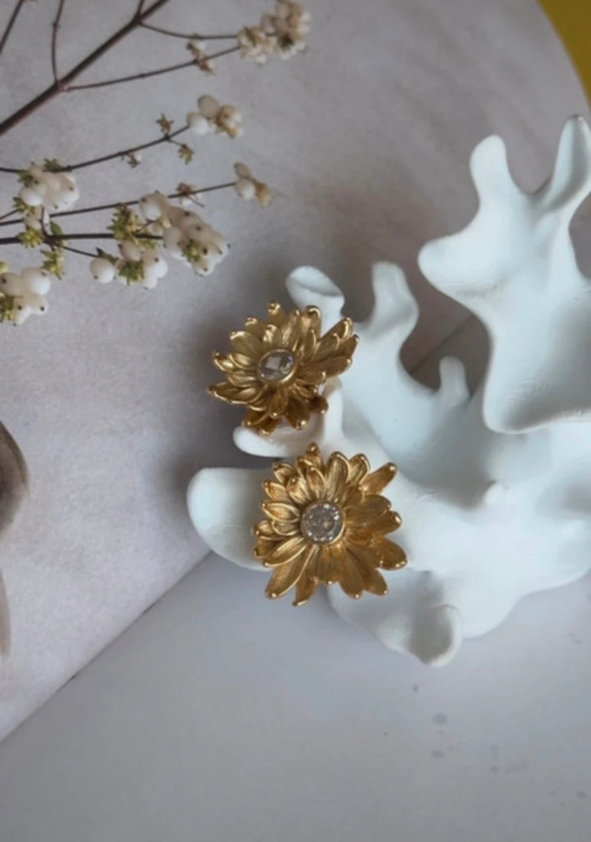 Pendientes Crisantemi dorados con flores blancas en composición editorial