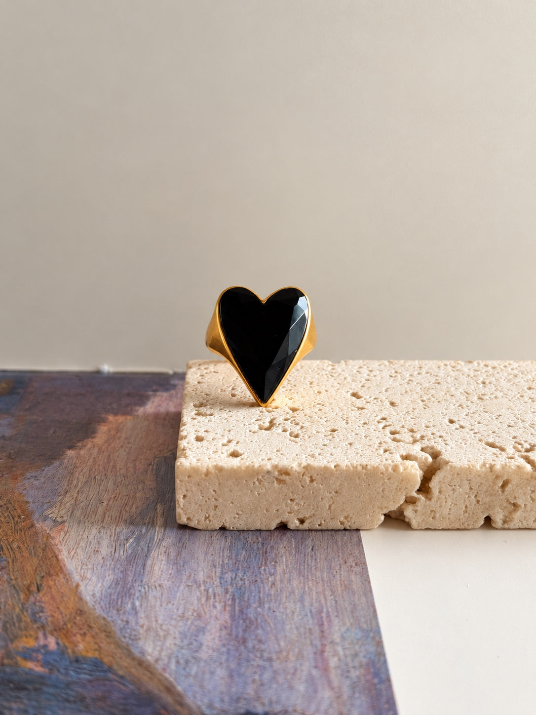 Anillo L’Amour en clair-obscur de Ma Meilleure Symphonie, corazón negro facetado en acabado dorado, vista frontal sobre piedra