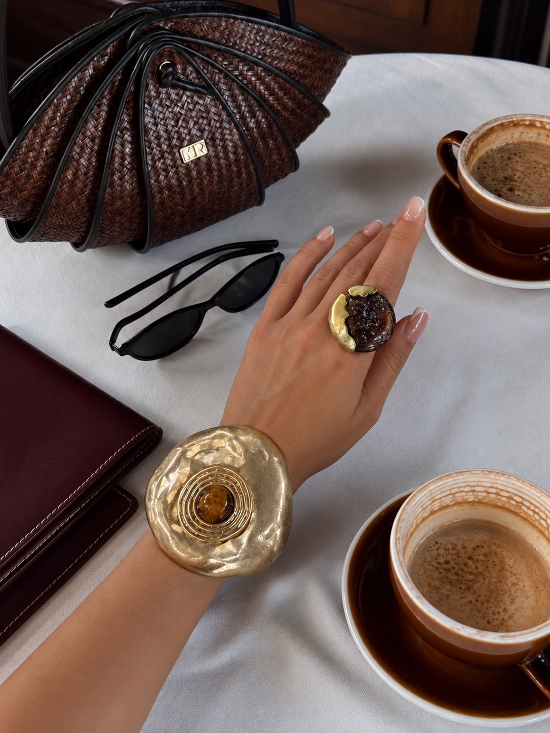 Anillo escultórico y brazalete dorado en una mesa de café