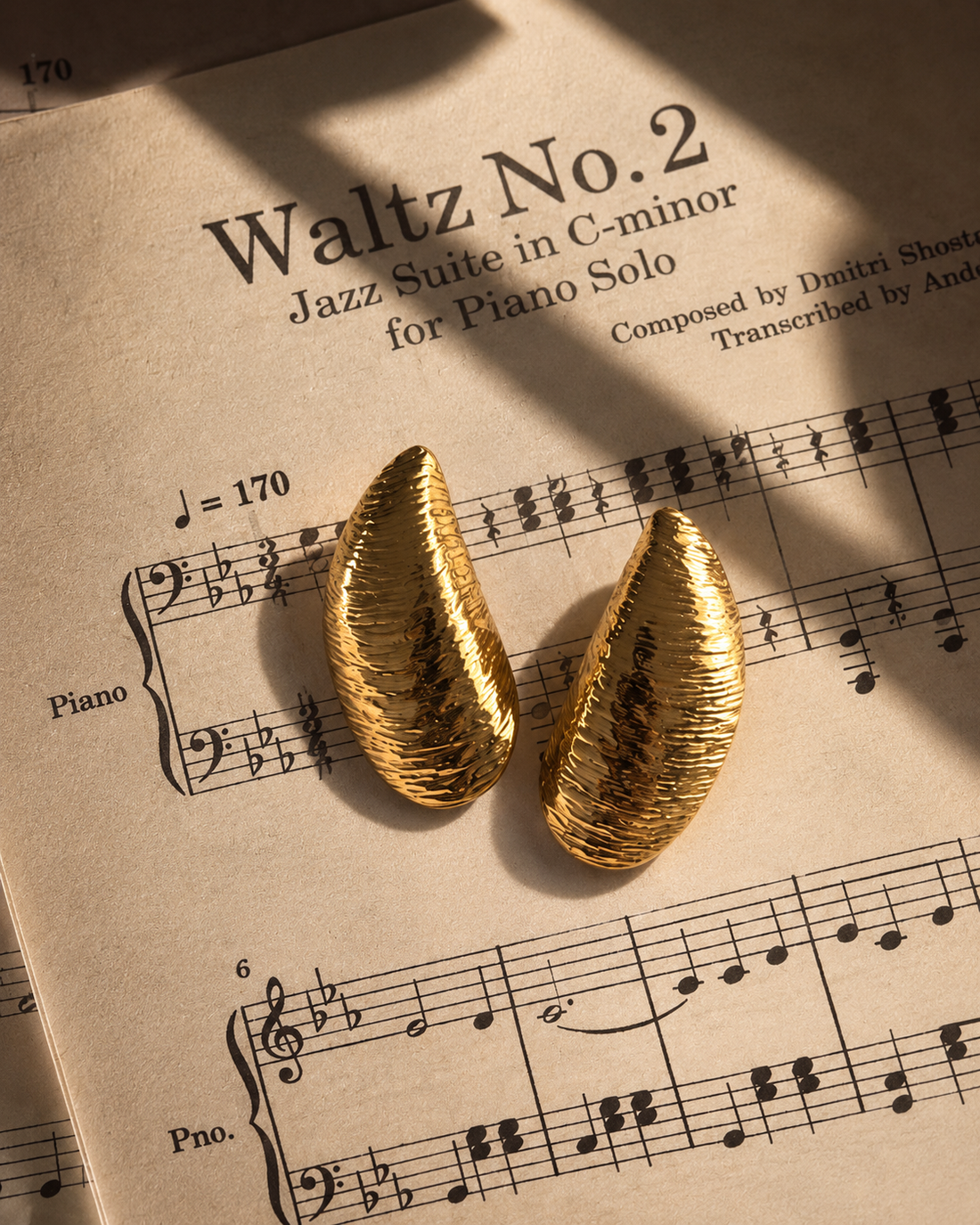 Pendientes dorados sobre una partitura musical