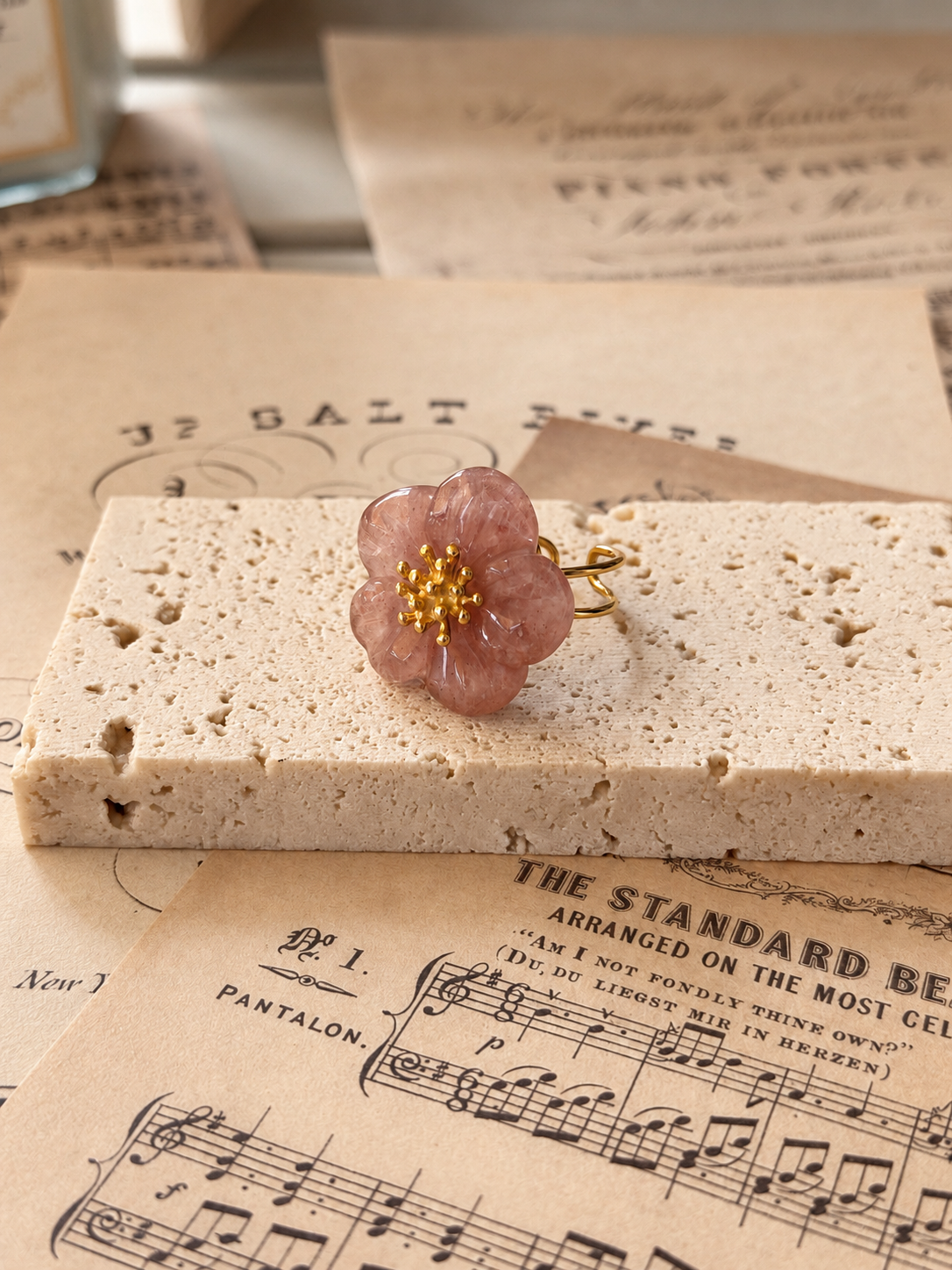 Anillo de flor rosa empolvado sobre partituras antiguas