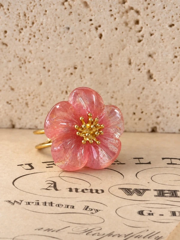 Anillo de flor rosa translúcida sobre piedra y partituras