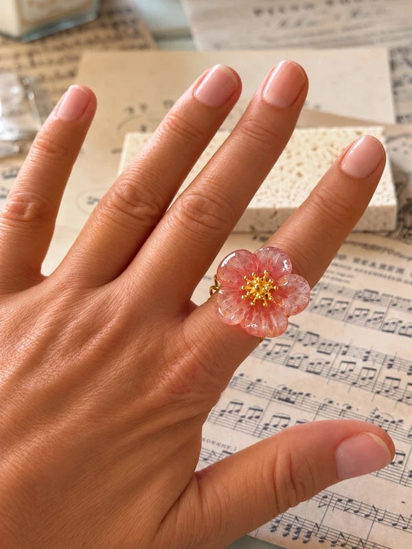 Anillo de flor rosa translúcida sobre la mano