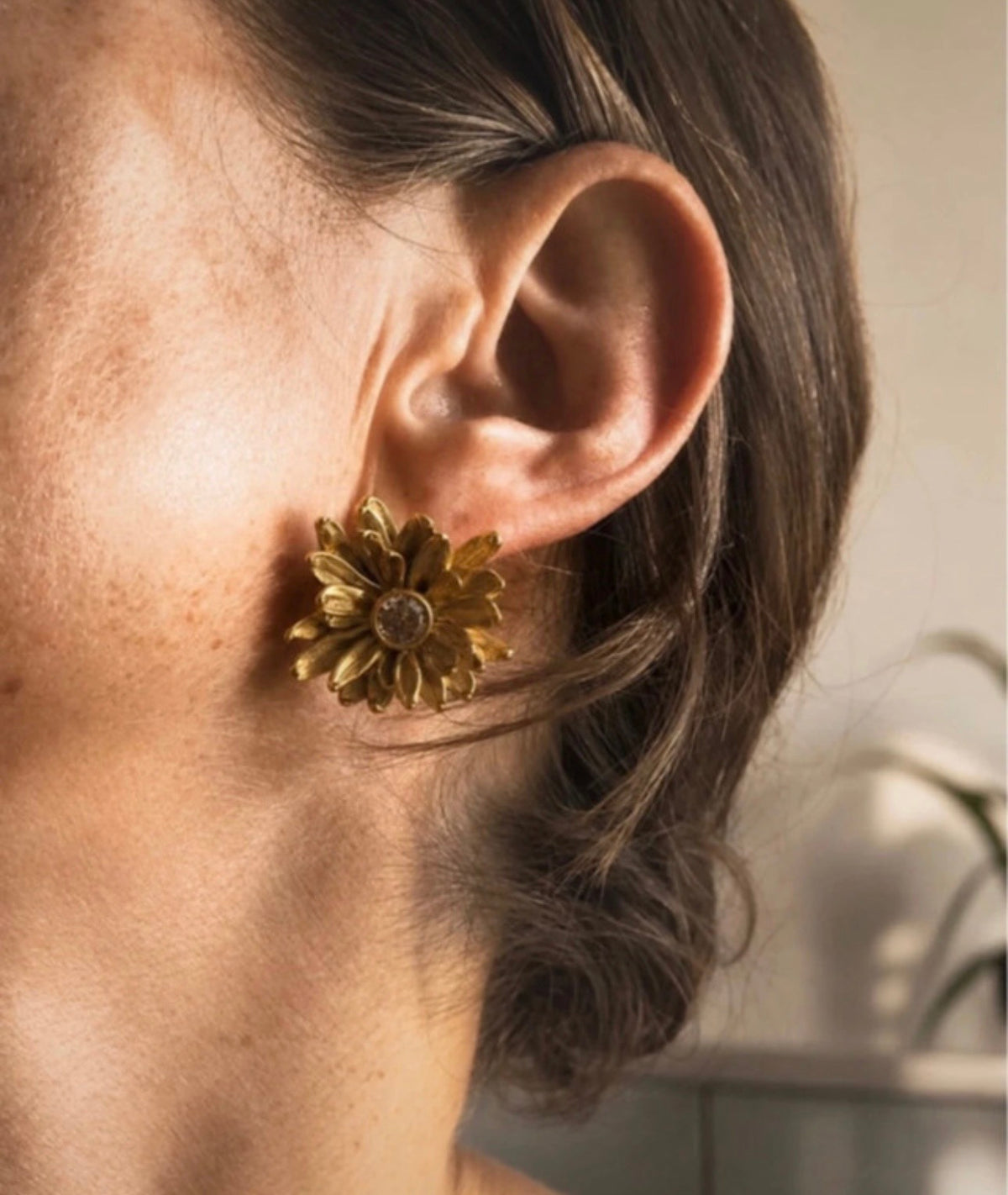 Pendiente Crisantemi dorado puesto, detalle floral con cristal