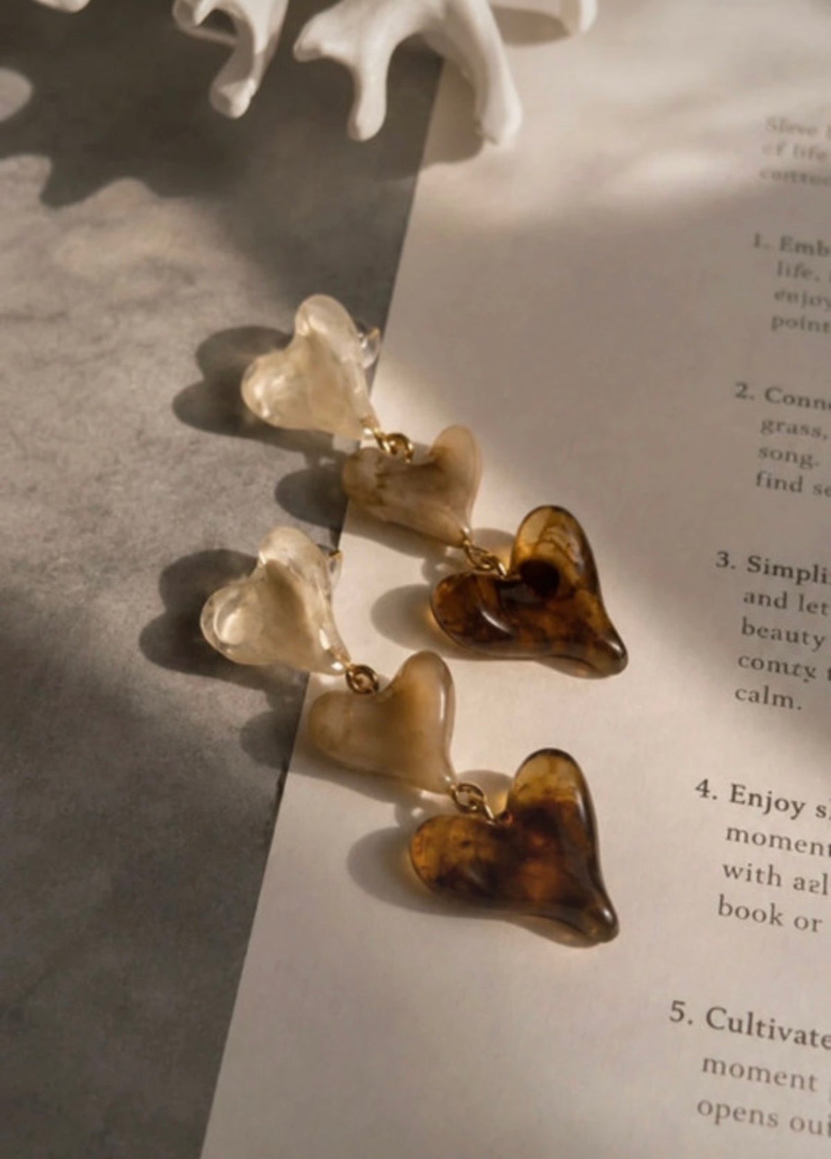 Pendientes de corazones translúcidos en tonos ámbar sobre libro