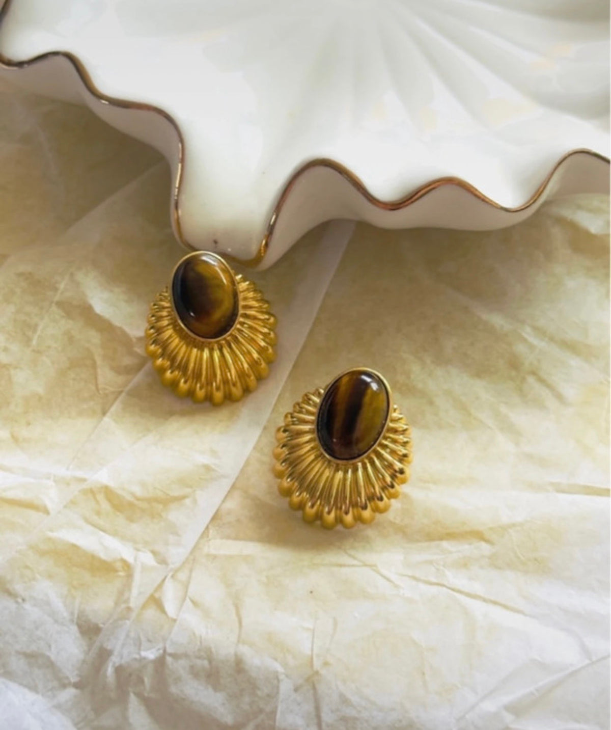 Pendientes vintage dorados con piedra ojo de tigre en composición editorial